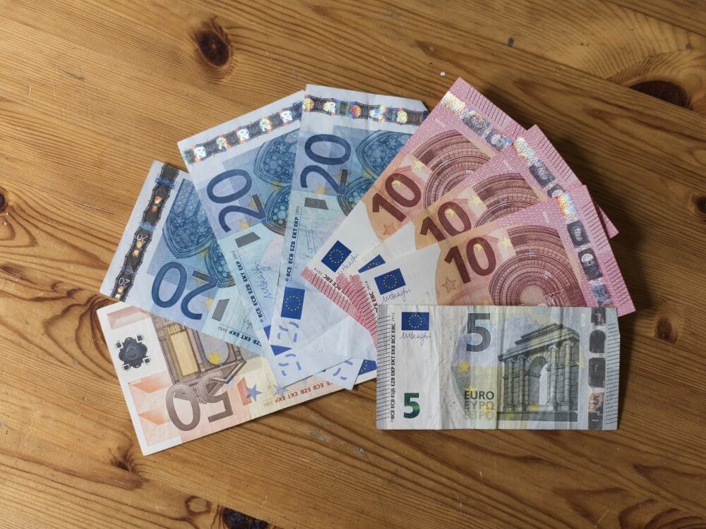 Geldscheine liegen zu einem Fächer angeordnet auf einem Holztisch