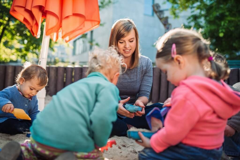 Eine junge Frau und zwei Kinder spielen draußen