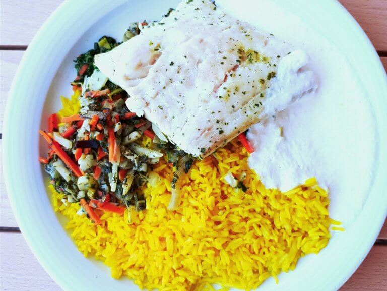 Reis, Fisch und gemüse auf einem weißen Teller